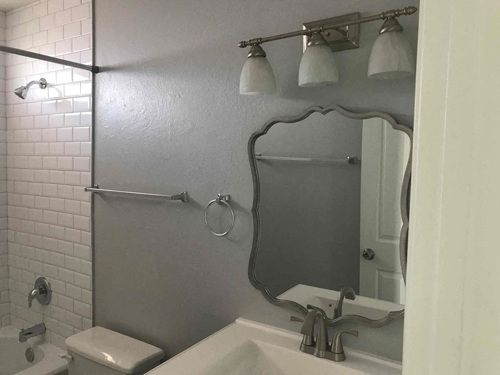 A bathroom with a toilet, sink, and mirror.