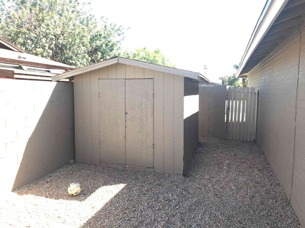 A concrete shed with a gravel ground and a ball on it.