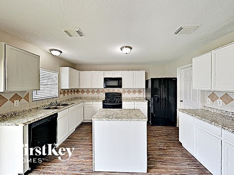 a white kitchen with granite counter tops and black appliances