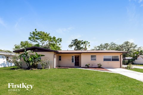 a small tan house with a lawn and a driveway