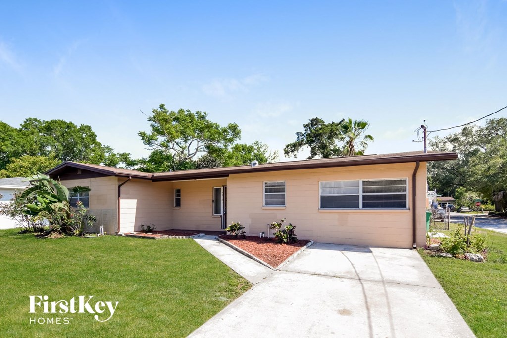 a small tan house with a sidewalk and grass