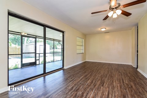 the living room of an empty house with wood flooring and a ceiling fan