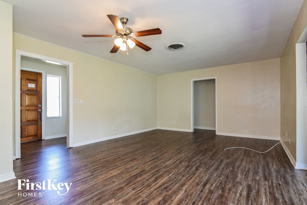 the living room of an empty house with wooden floors and a ceiling fan