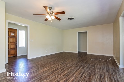 the living room of an empty house with wooden floors and a ceiling fan