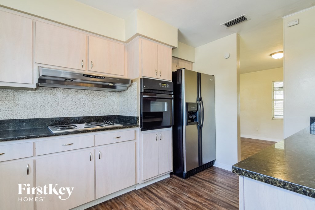 a kitchen with white cabinets and black counter tops and a refrigerator