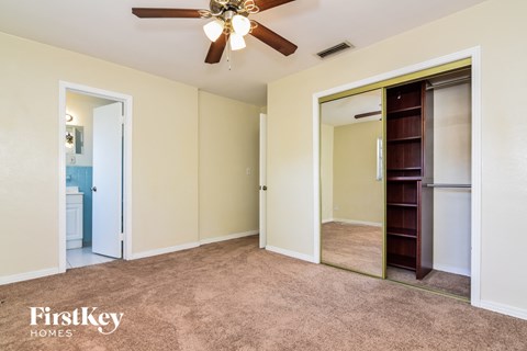 an empty bedroom with a closet and a ceiling fan