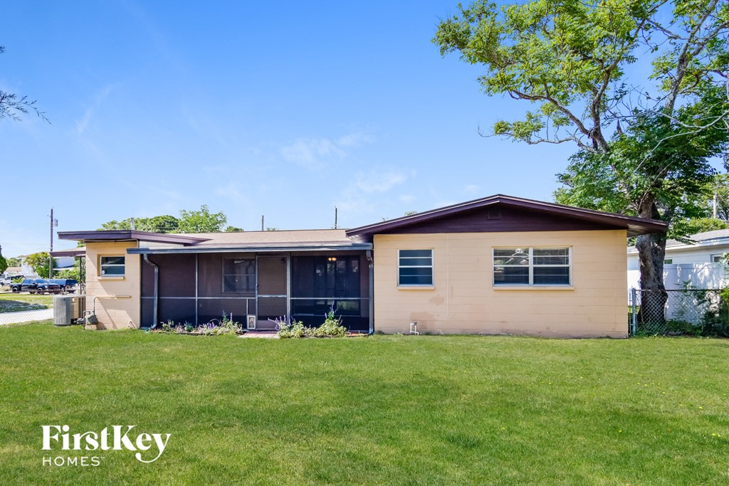 a small tan house with a yard and a tree