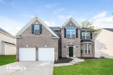 a brick house with two garage doors and a lawn