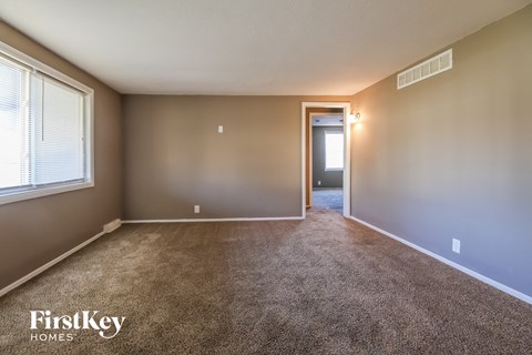 an empty living room with carpet and a door to a hallway