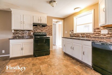 a kitchen with white cabinets and black appliances and a brick wall