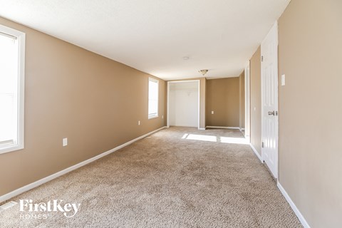 a spacious living room with carpet and a door to a hallway