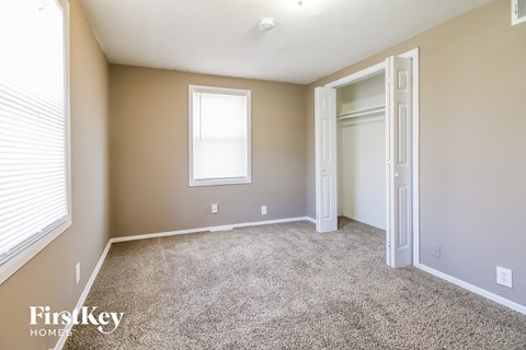 a bedroom with carpet and a closet and a window