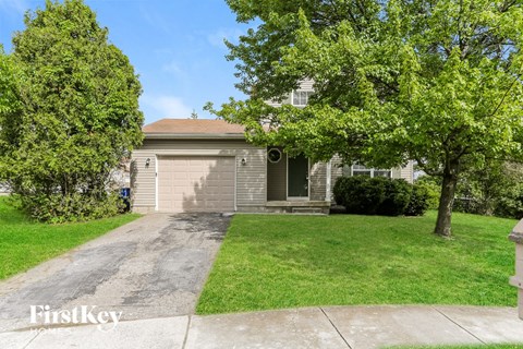 A house with a driveway and trees in front of it.