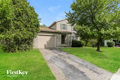 A house with a driveway and a tree in front of it.