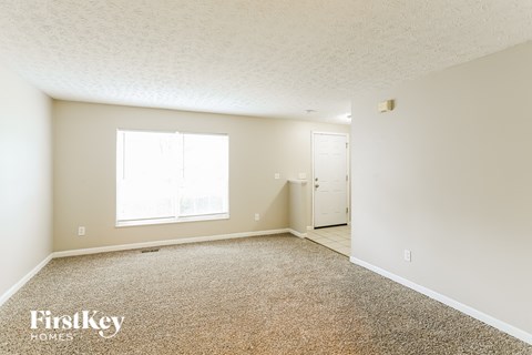 A room with a carpeted floor and a window letting in natural light.