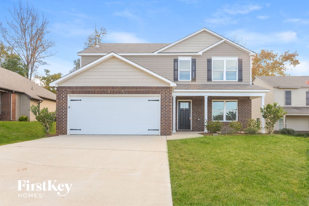 a brick house with a white garage door in front of a lawn