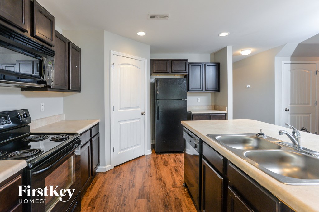 a kitchen with black appliances and white counters and wood flooring