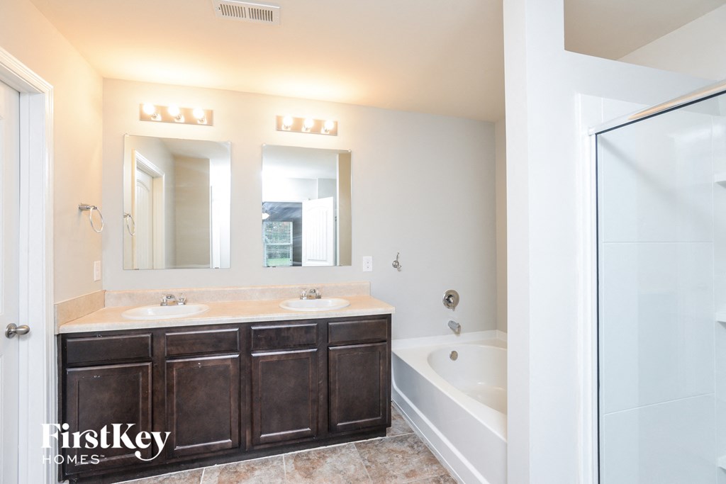 a bathroom with two sinks and a shower and a bath tub