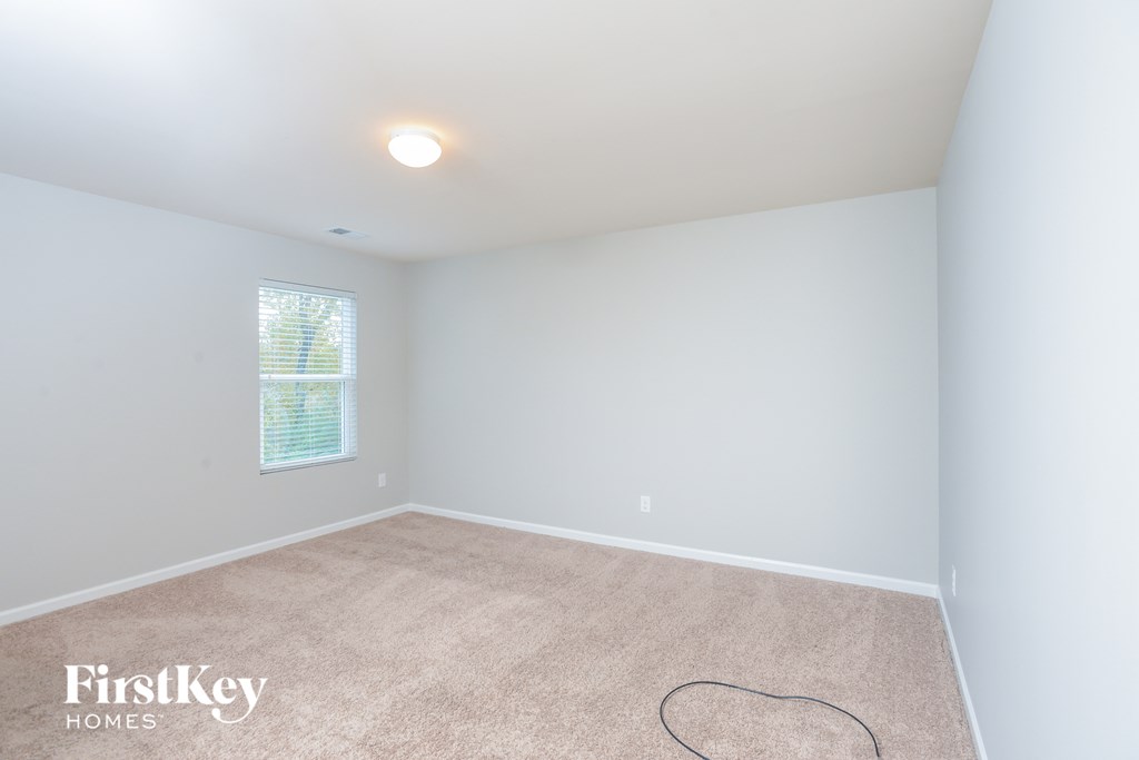 a bedroom with white walls and carpet and a window
