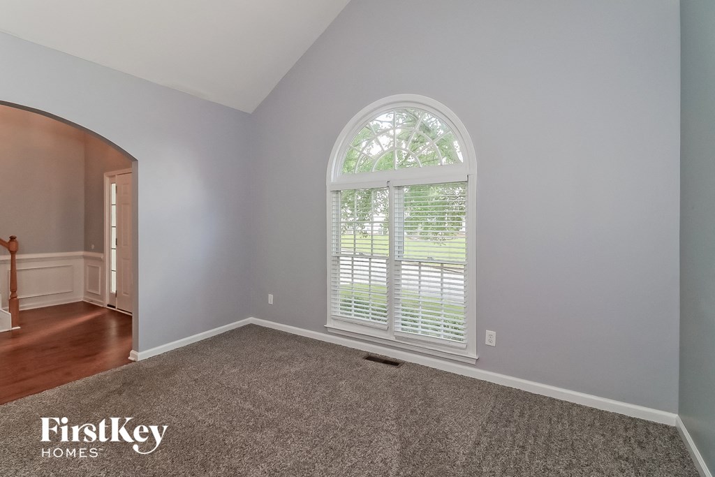 the master bedroom has a large arched window and gray carpet