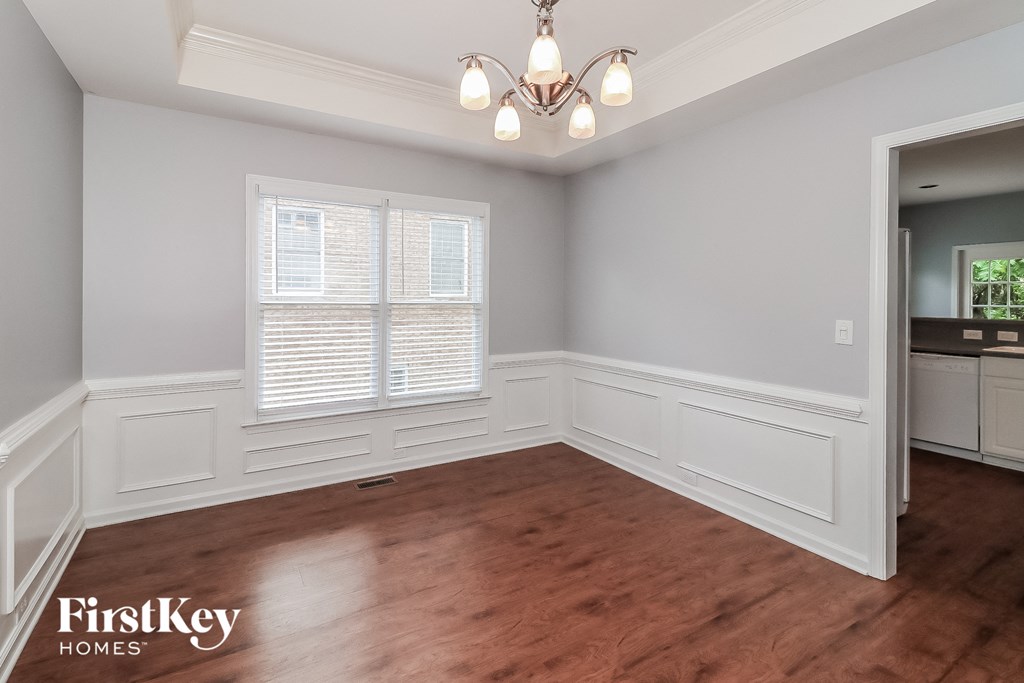 a dining room with white walls and wooden floors and a chandelier