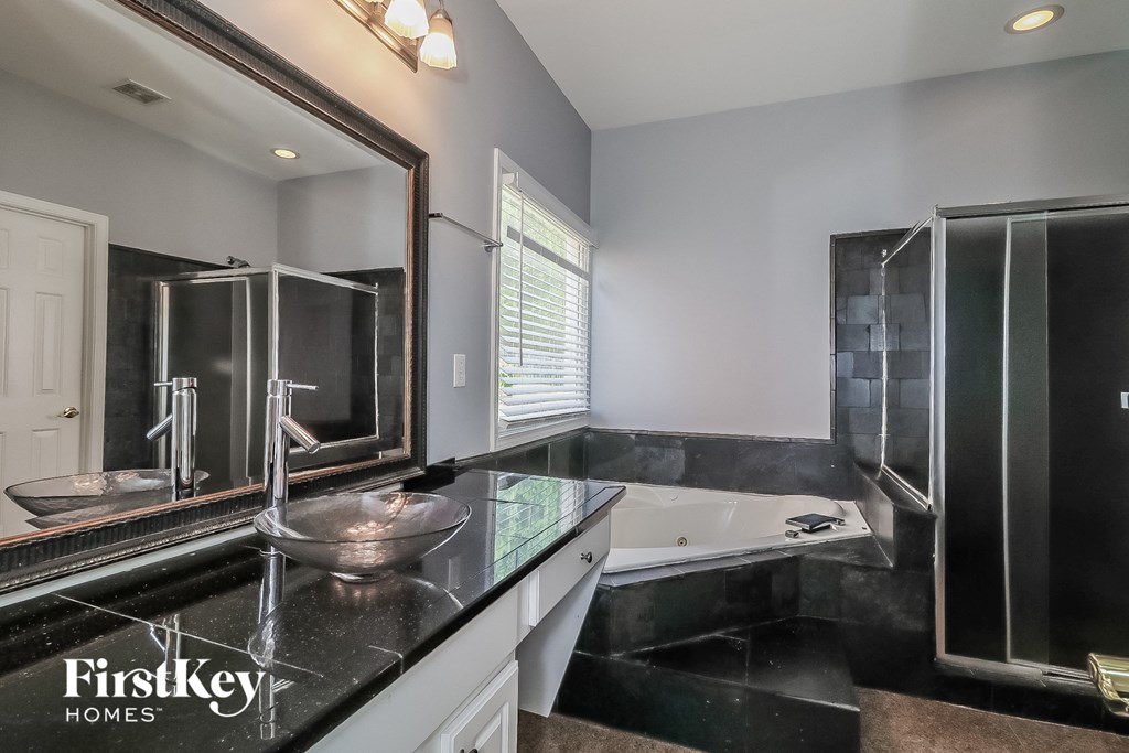 a black and white bathroom with a tub and sink and mirrors