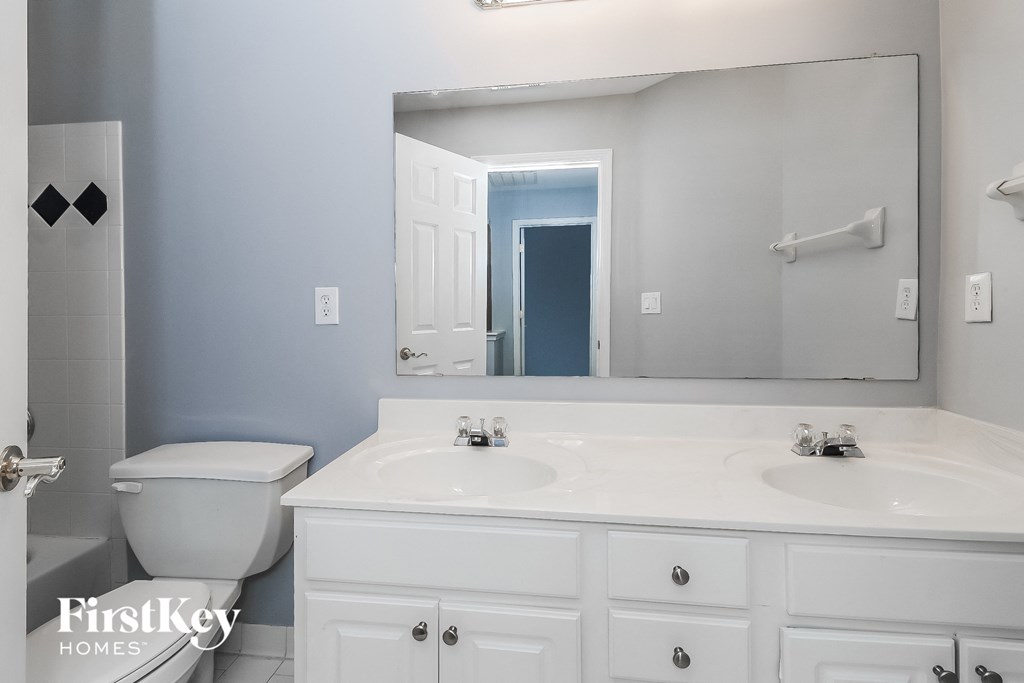 a white bathroom with a large mirror and a toilet and sink