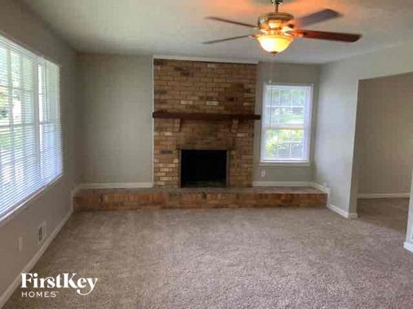 a living room with a brick fireplace and a ceiling fan
