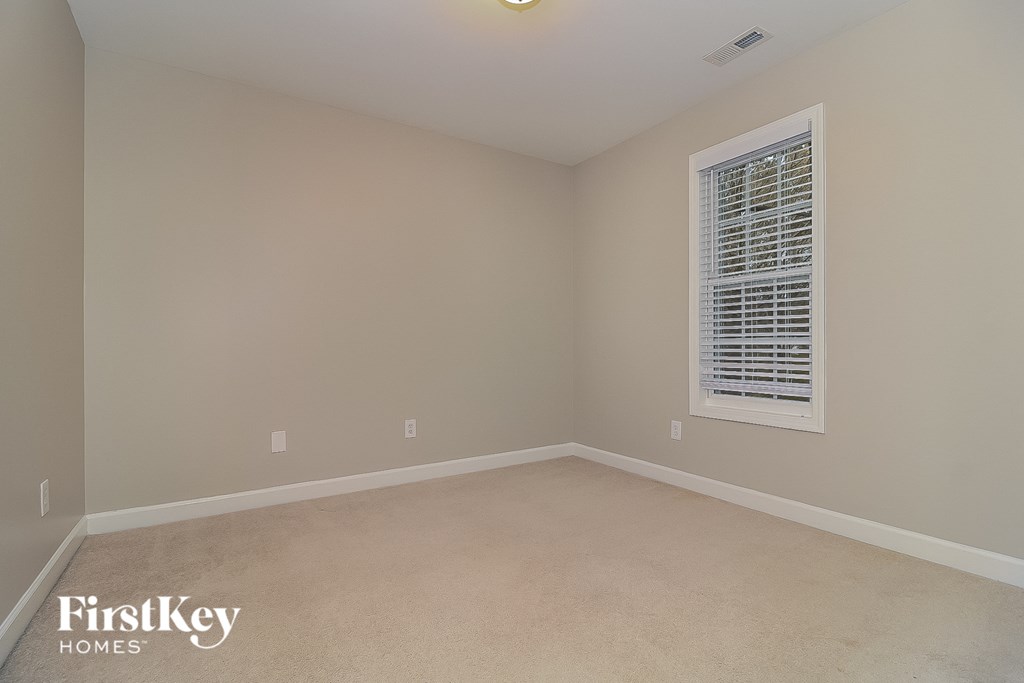 a bedroom with a window and a carpeted floor