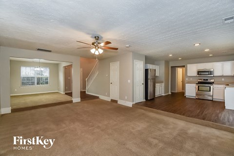 A spacious living room with a kitchen in the background.