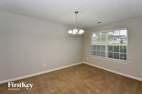 A room with a carpeted floor and a chandelier hanging from the ceiling.