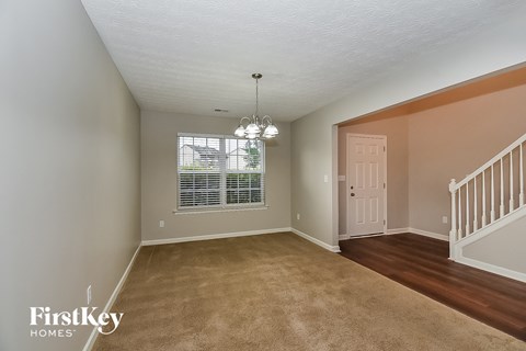 A room with a carpeted floor and a staircase.