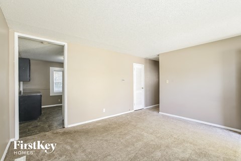 a living room with carpet and a door to a kitchen