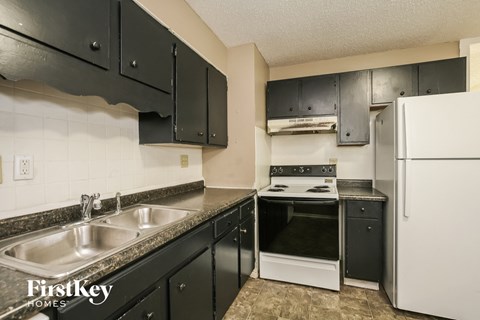 a kitchen with black cabinets and white appliances and a sink