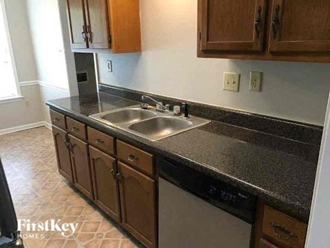 A kitchen with brown cabinets and a black countertop.