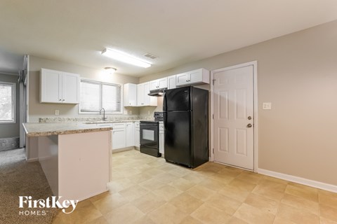 A kitchen with a black refrigerator and white cabinets.