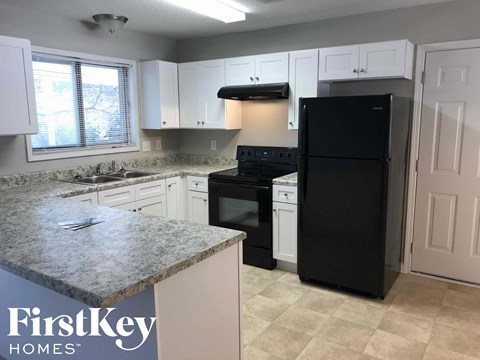 a kitchen with white cabinets and a black refrigerator
