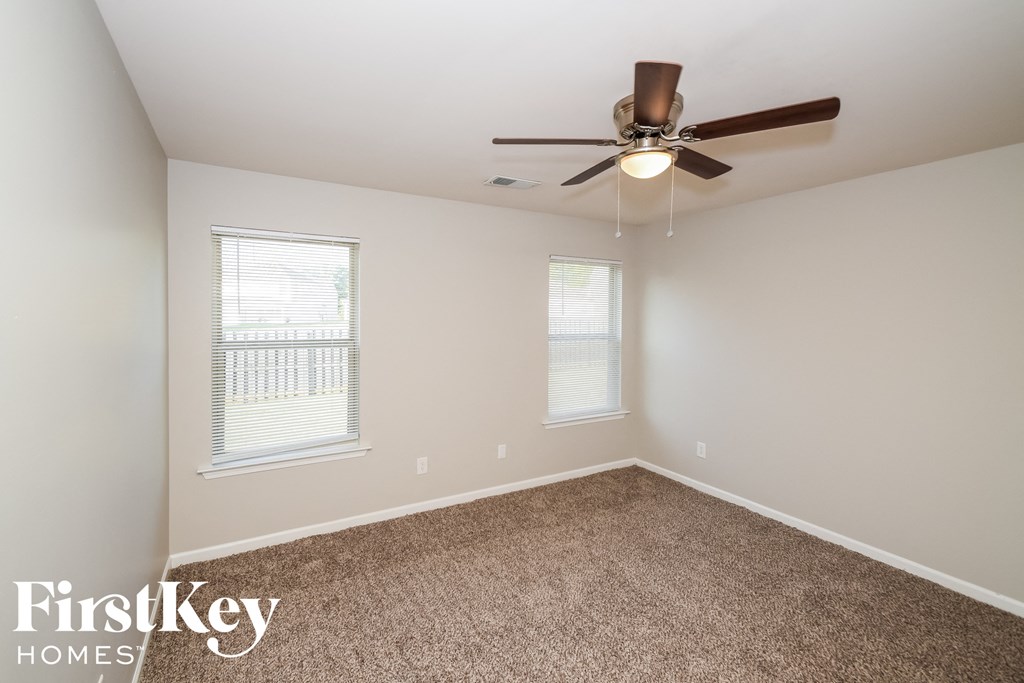 an empty room with a ceiling fan and two windows