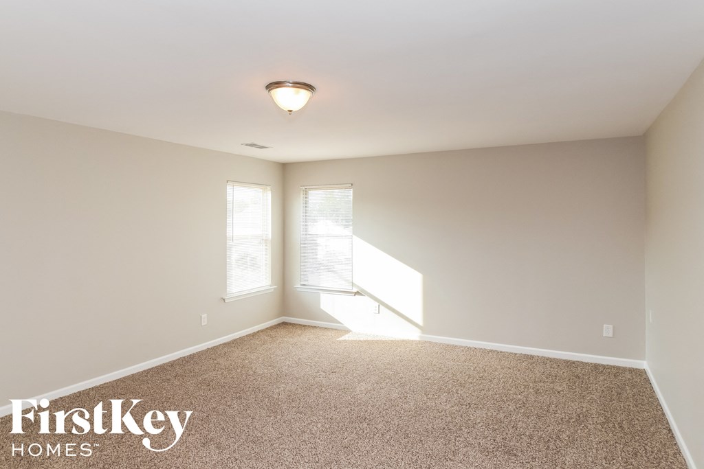 a empty living room with carpet and two windows