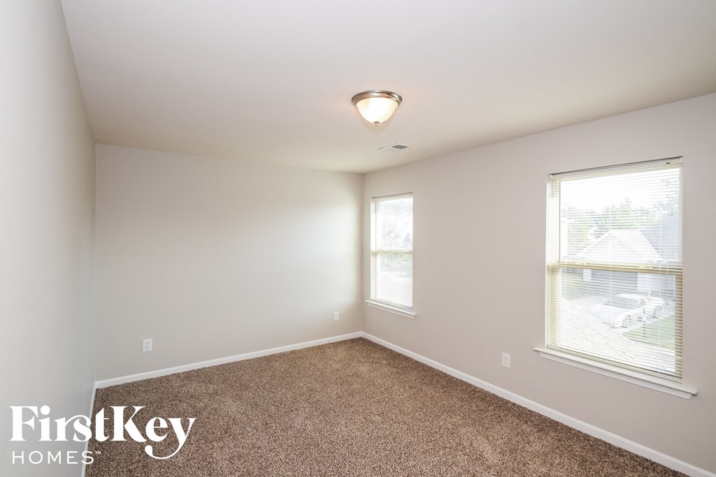 a bedroom with a carpeted floor and two windows