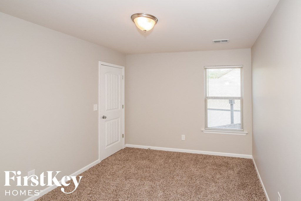 a bedroom with carpet and a door and a window
