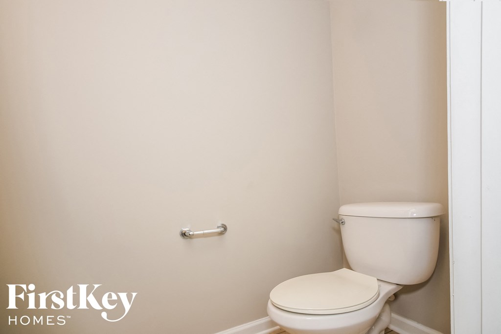 a bathroom with a toilet and a white wall