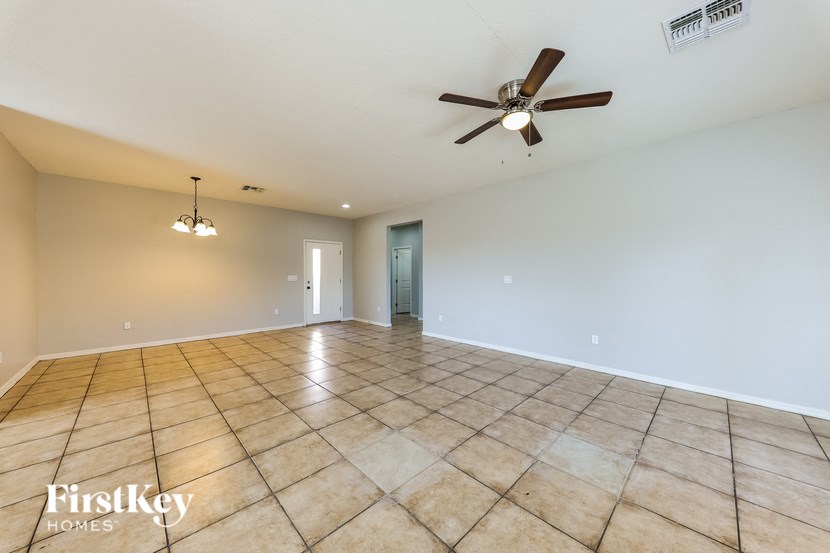 A spacious room with a ceiling fan and a light fixture on the wall.