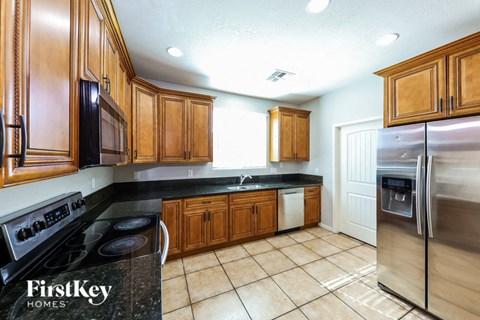 A kitchen with wooden cabinets and a stainless steel refrigerator.