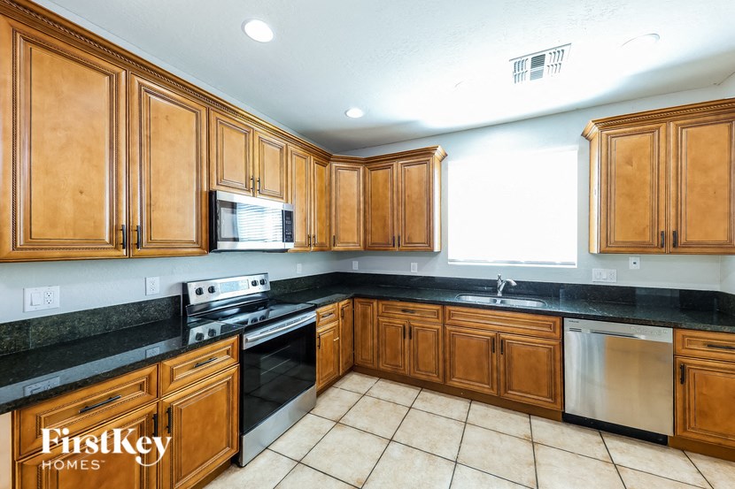 A kitchen with wooden cabinets and black countertops.