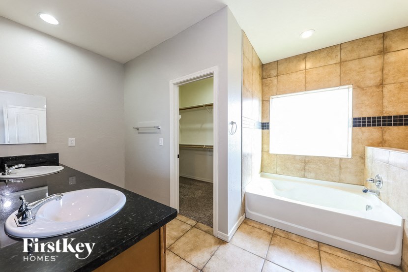 A bathroom with a black countertop and a white bathtub.