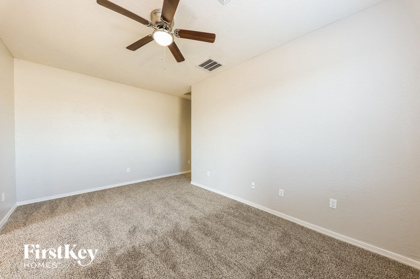 A room with a ceiling fan and carpeted floor.
