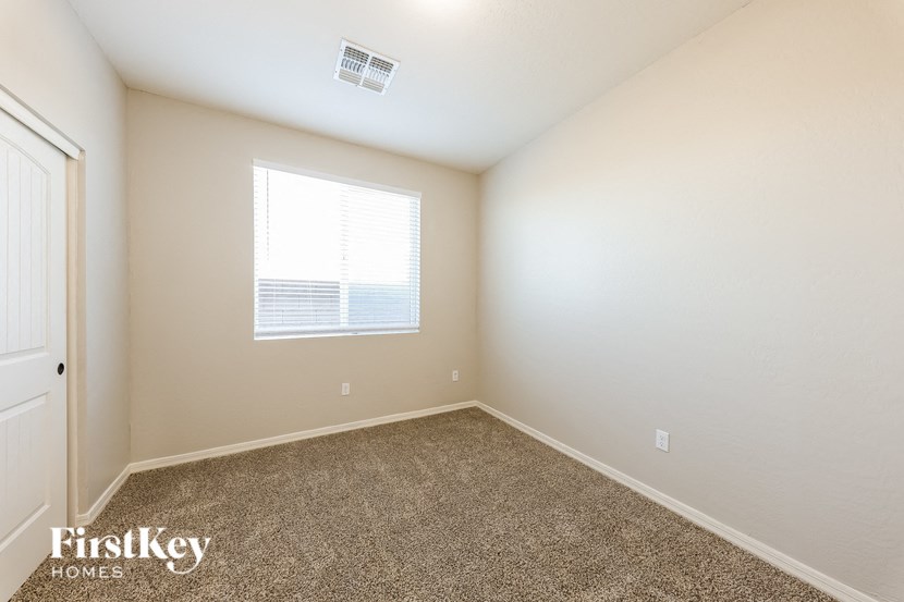 A room with a carpeted floor and a window with blinds.
