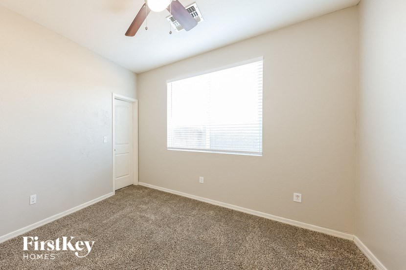 A room with a carpet floor and a window with blinds.