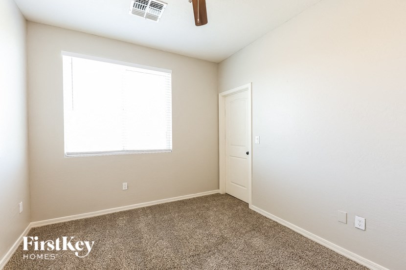 A room with a carpeted floor, a door, and a window.